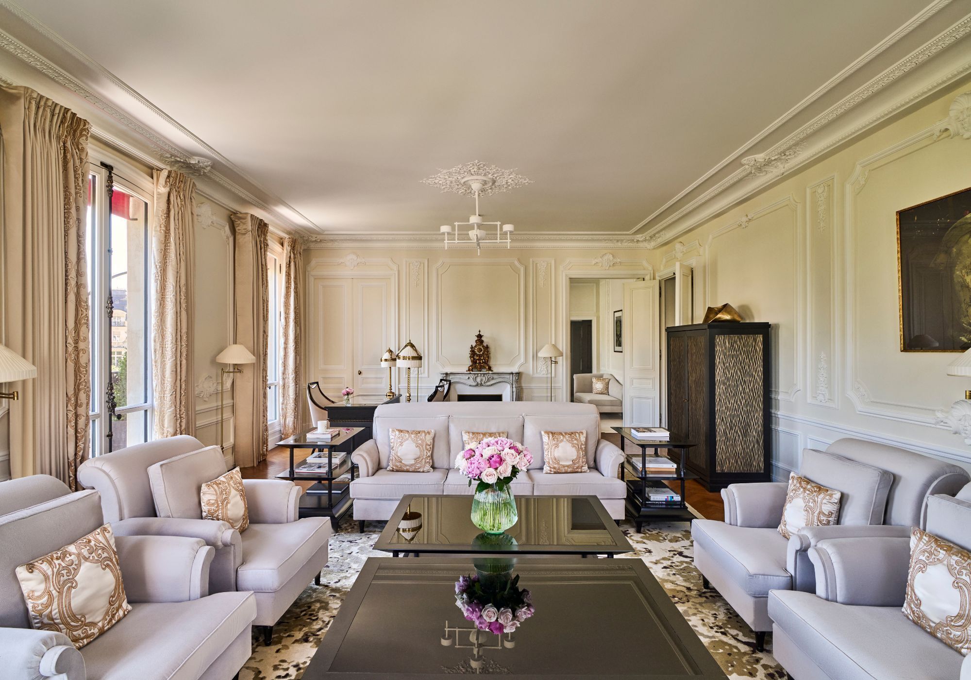 A spacious living room with a sofa set, a coffee table with a vase, and a chandelier.