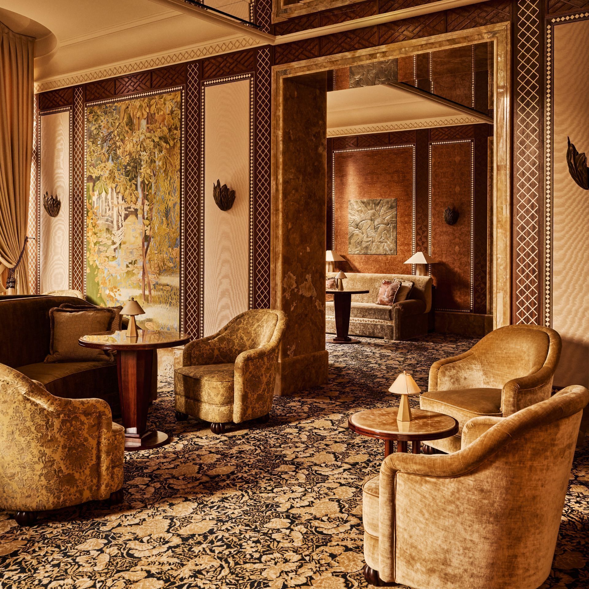 Un vestíbulo lujoso con paneles de madera ornamentados, un gran tapiz floral y sillones clásicos.