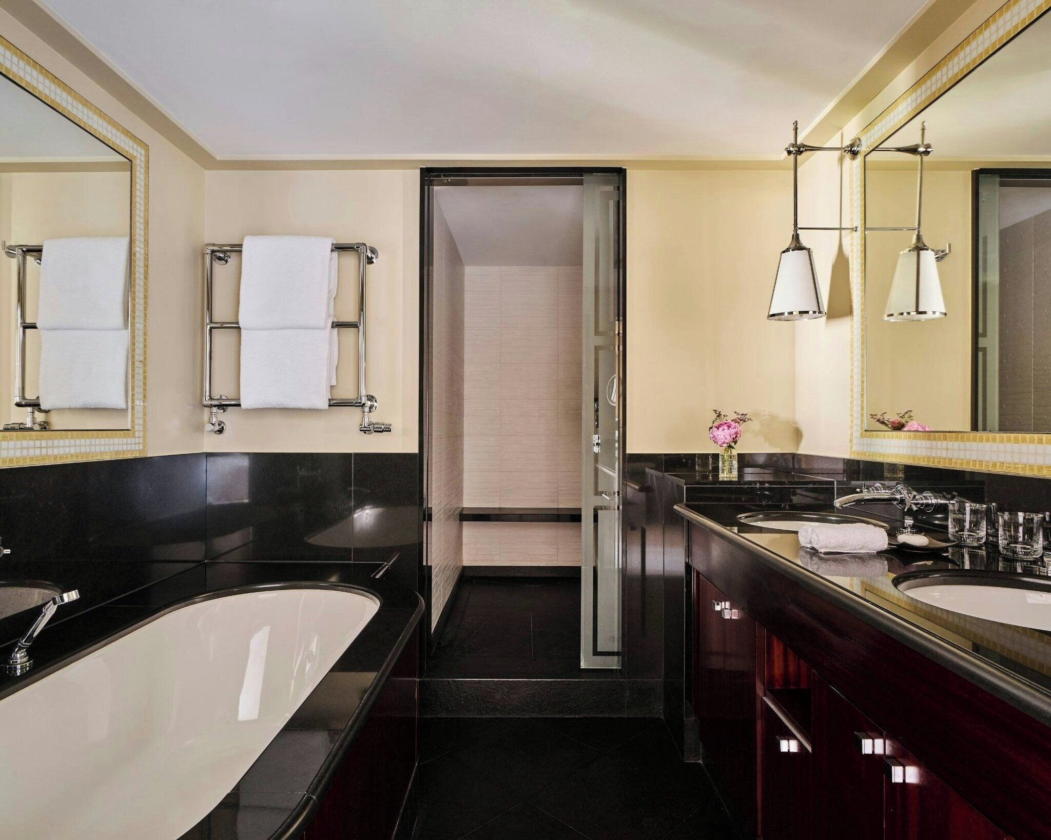 A modern bathroom with a large bathtub, two sinks, and a shower.