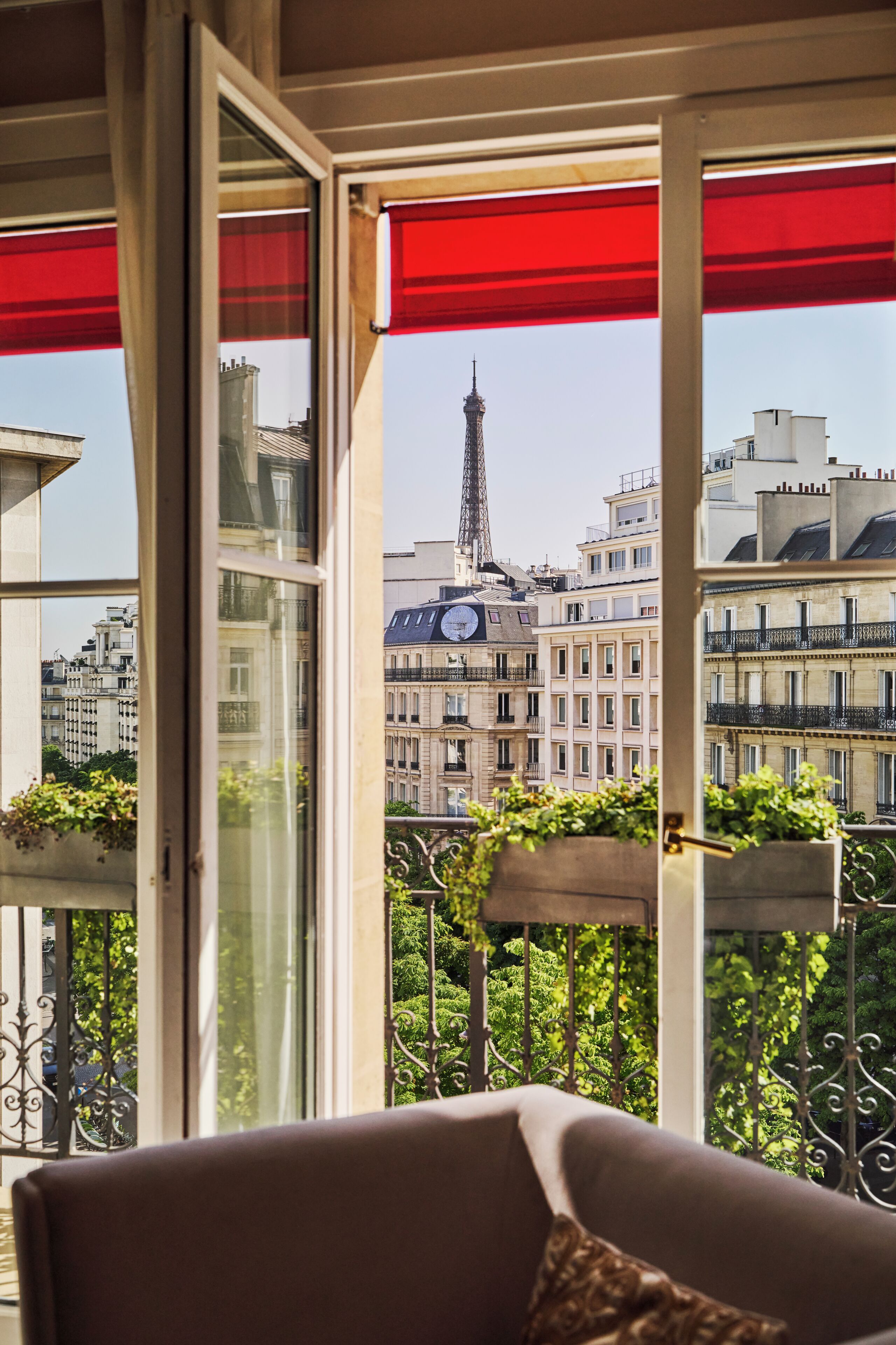 Un balcon avec vue sur la Tour Eiffel, une balustrade en fer forgé et un pot de fleurs.