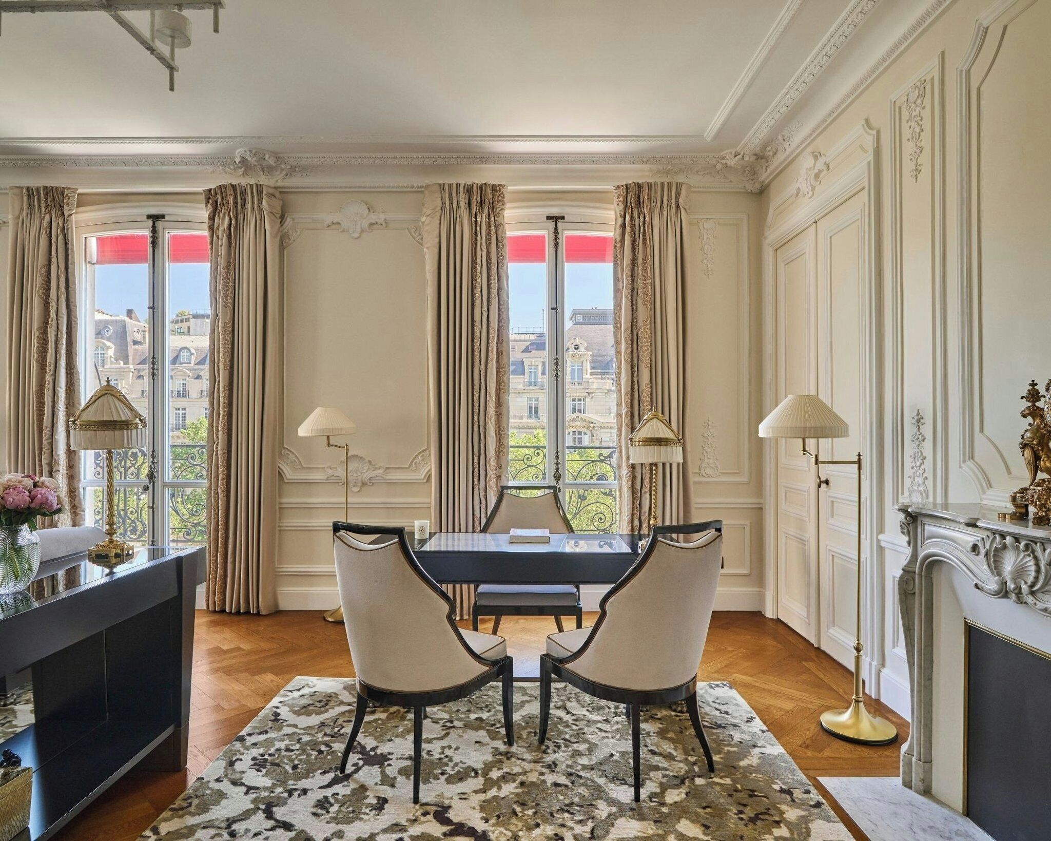 A dining room with a table, chairs, and a view through large windows.