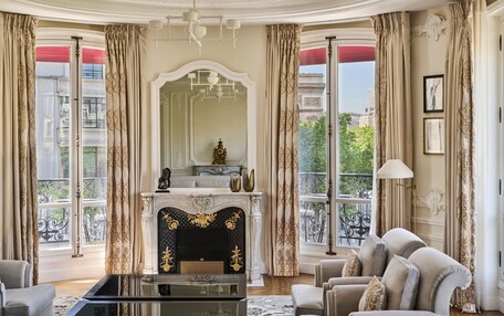 A luxurious room with a fireplace, elegant furniture, and large windows with curtains.