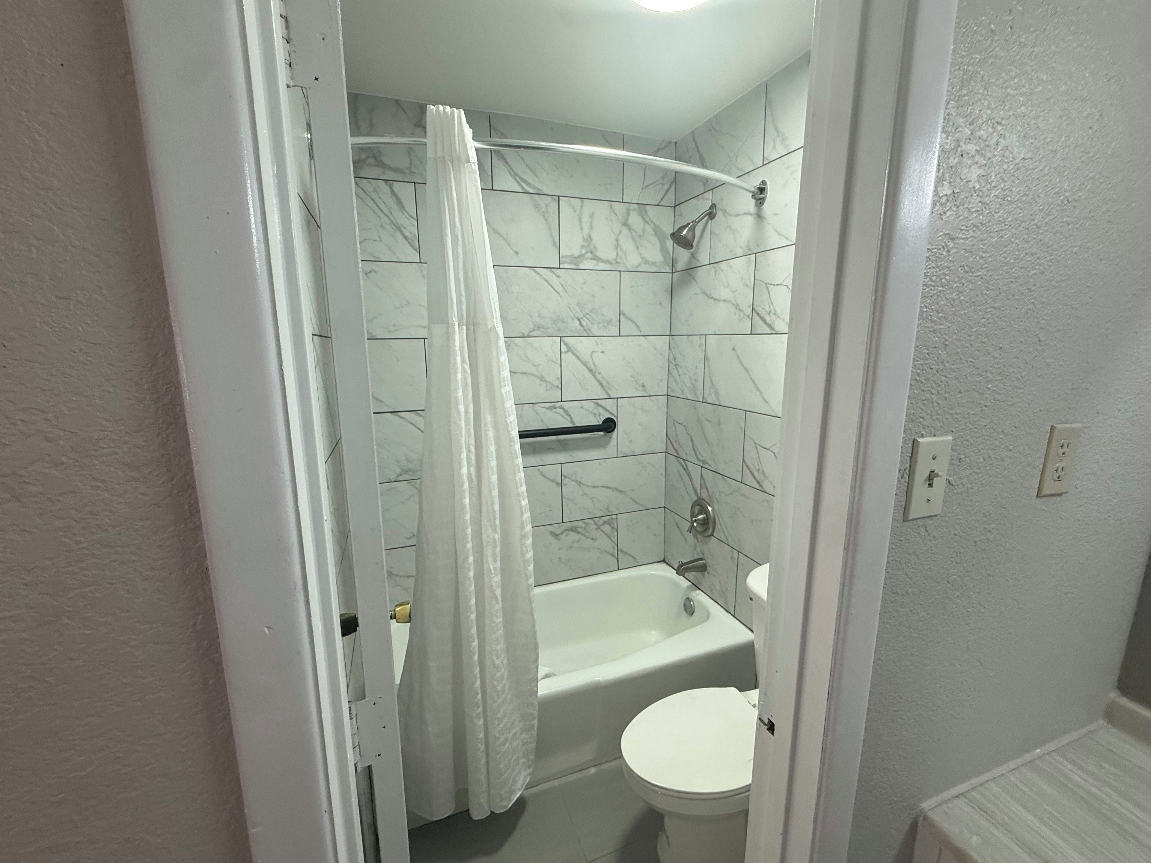 Un baño con bañera, inodoro y cortina de ducha.