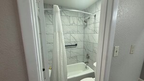 A bathroom with a bathtub, toilet, and shower curtain. - Red Roof Inn Shamrock (Shamrock)
