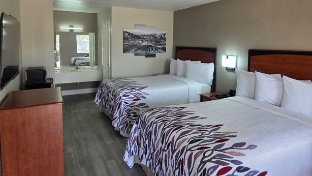 A hotel room with two beds, a desk, a television, and a window. - Red Roof Inn Shamrock (Shamrock)