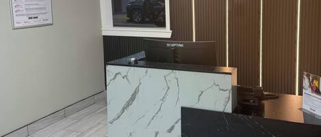 A reception desk with a marble top, a Sceptre brand monitor, and a Red Roof pet-friendly sign.