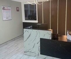 Un mostrador de recepción con encimera de mármol, un monitor de la marca Sceptre y un letrero que indica que el hotel Red Roof admite mascotas.