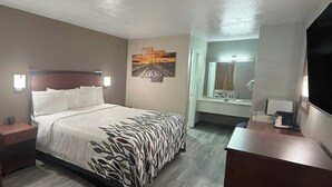 A hotel room with a bed, bedside tables, a desk, a mirror, and a wall with a road sign artwork. - Red Roof Inn Shamrock (Shamrock)
