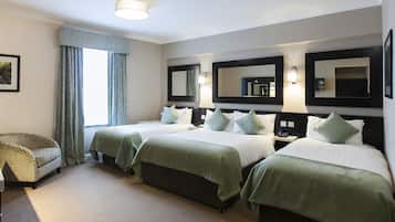 Habitación de hotel con dos camas, una silla y una mesita de noche.