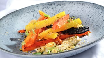 A plate of food with various vegetables and a creamy sauce.