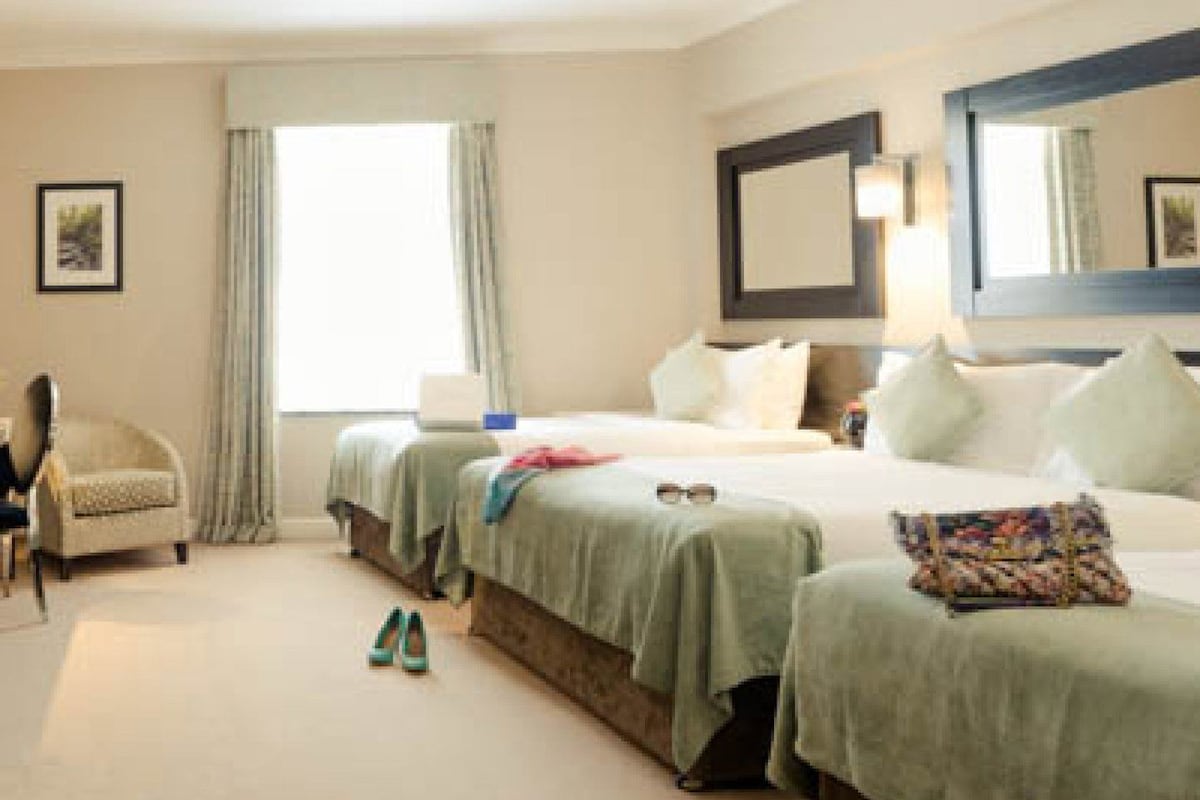 A hotel room with a bed, a chair, a desk, and a window.