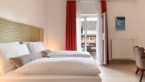 Une chambre d’hôtel avec un lit, une chaise, un radiateur et une affiche accrochée au mur.
