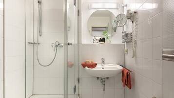 A modern bathroom with a glass-enclosed shower, a white sink, and a mirror.