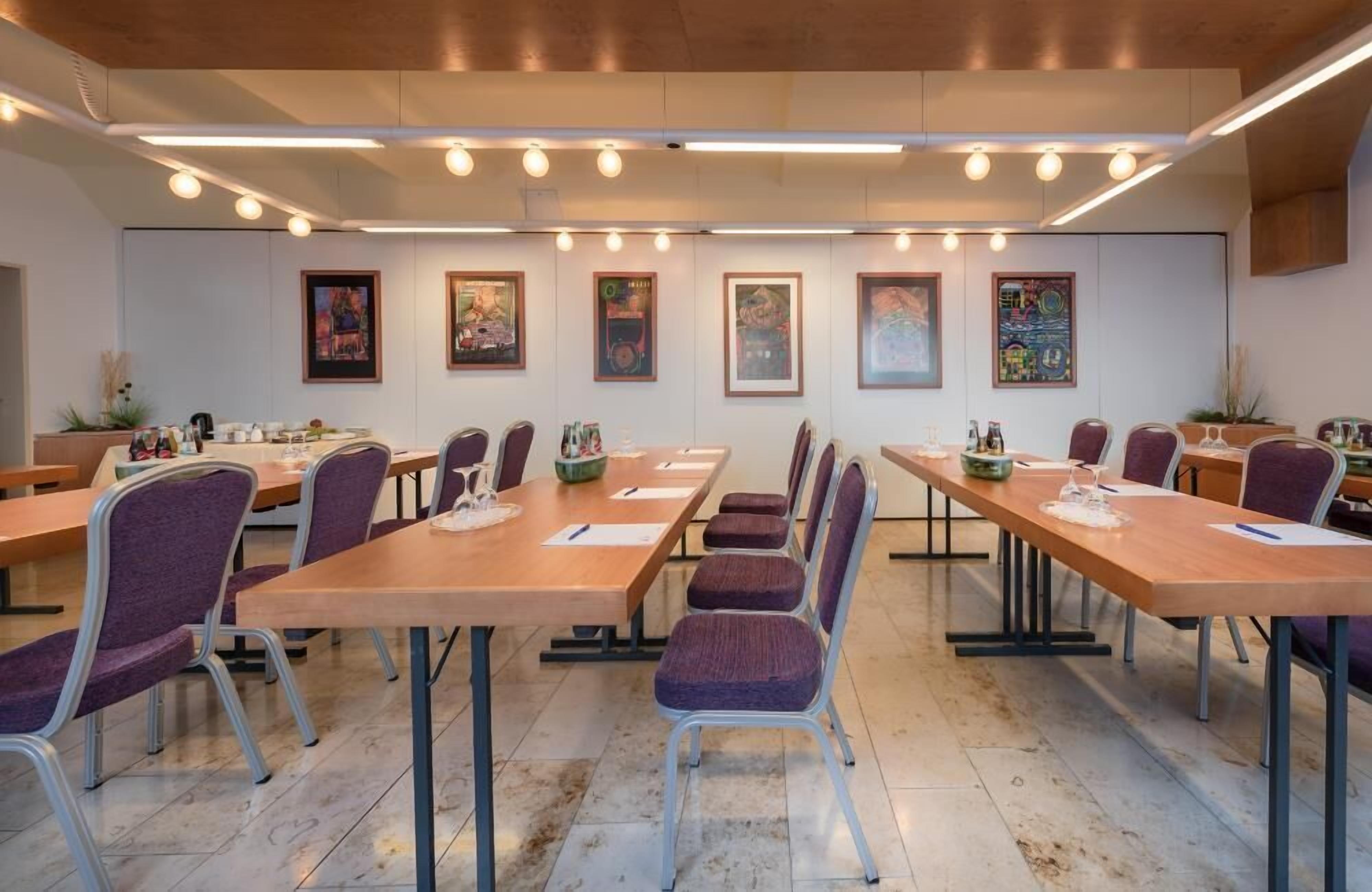 A conference room with long tables and chairs, framed artwork on the walls, and a clean, modern design.