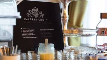 A black sign with white text and a crest, surrounded by stacks of glass jars and bowls on a wooden table.