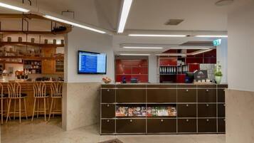 A reception area with a bar, wooden chairs, a computer monitor, and a plant.