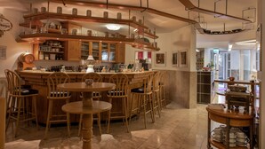 Un espace bar avec des meubles en bois, des étagères remplies de verres et un appareil à café.