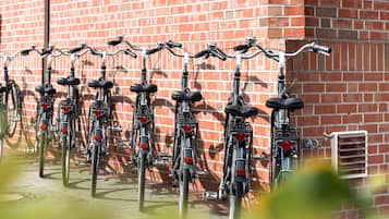 Een rij fietsen geparkeerd tegen een bakstenen muur.