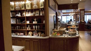 A hotel lobby with wooden decor, a counter with food and drinks, and a view of the street.