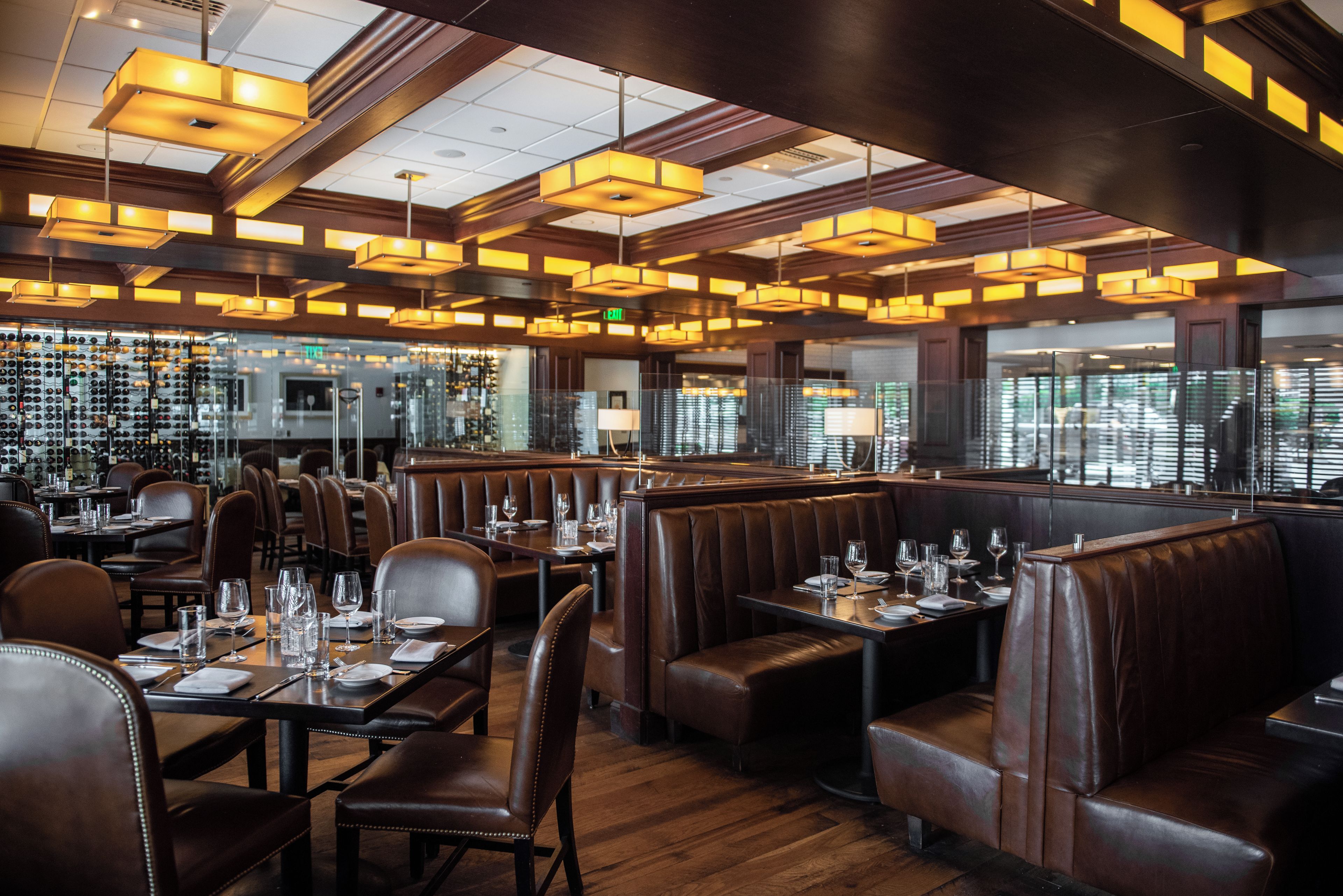 L'intérieur d'un restaurant avec des banquettes, un plancher en bois et des luminaires suspendus.