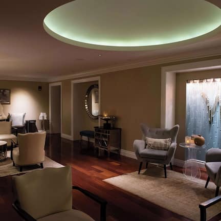 A spacious living room with multiple seating areas, a large mirror, and a window with patterned curtains.