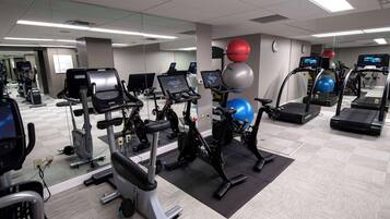 A gym with various exercise equipment, including treadmills, stationary bikes, and exercise balls.