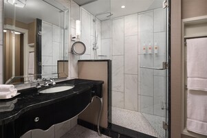 Un bagno moderno con un lavabo in marmo nero, uno specchio grande e una cabina doccia in vetro.