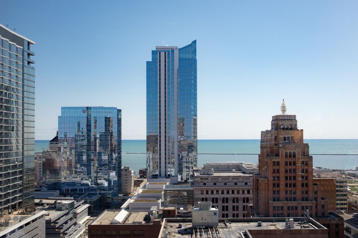 A cityscape with modern and historic buildings, a clear sky, and a view of the sea.