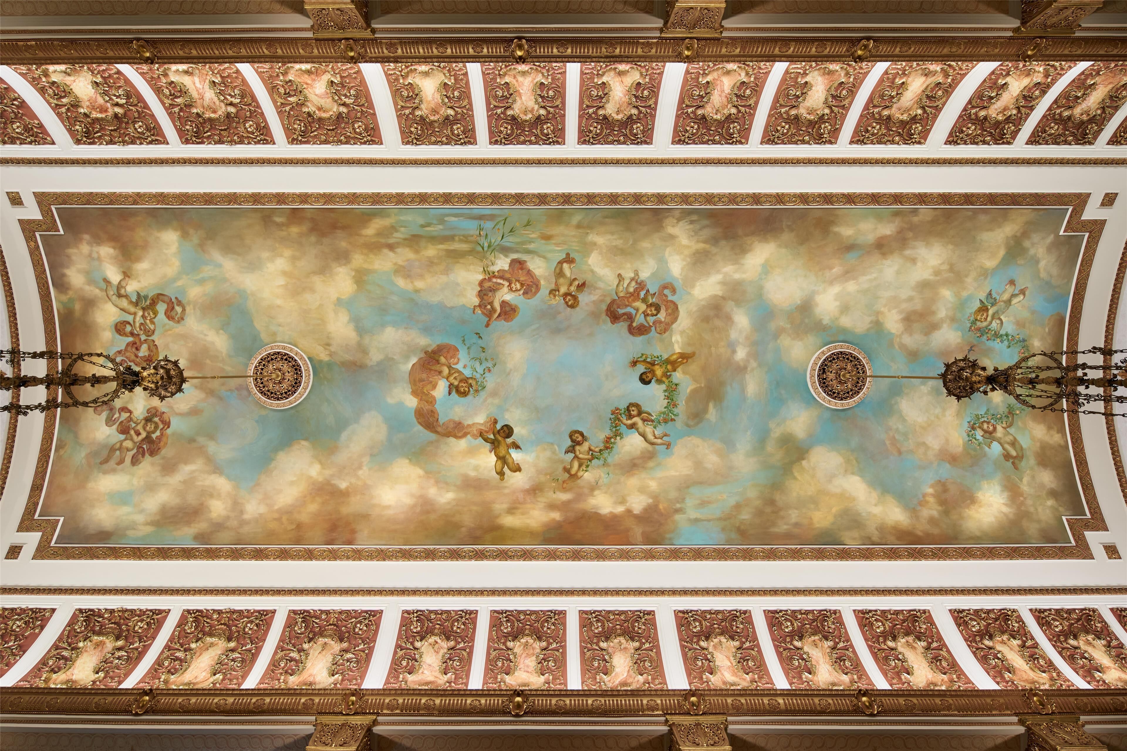 A ceiling with ornate gold and white decorations, including cherubs and floral motifs.