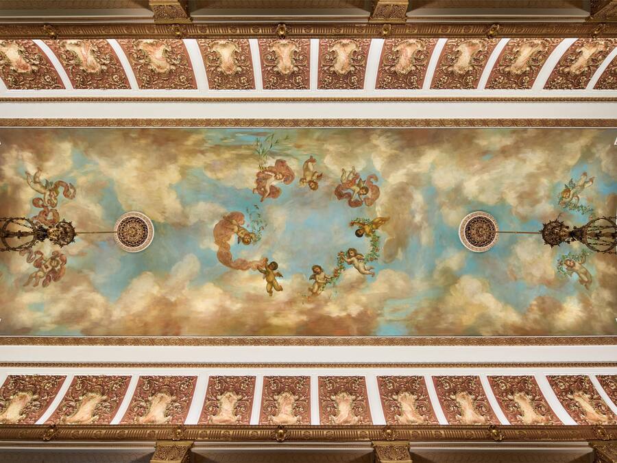 A ceiling with ornate gold and white decorations, including cherubs and floral motifs.