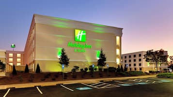Un hôtel Holiday Inn & Suites, reconnaissable à son grand panneau, son parking et les bâtiments qui l’entourent.