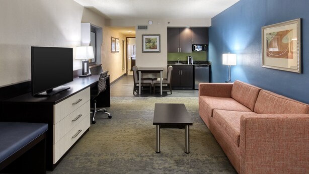 A hotel room with a TV, desk, chair, sofa, and kitchenette. - Holiday Inn Hotel & Suites Atlanta Airport-North by IHG (Atlanta)