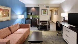 A compact hotel room with a kitchenette, a sofa, a dining table, and a TV. - Holiday Inn Hotel & Suites Atlanta Airport-North by IHG (Atlanta)
