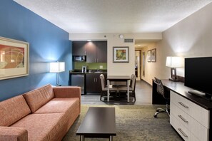 A compact hotel room with a kitchenette, a sofa, a dining table, and a TV. - Holiday Inn Hotel & Suites Atlanta Airport-North by IHG (Atlanta)