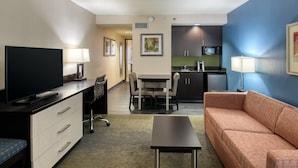 A hotel room with a TV, desk, chair, sofa, dining table, and kitchen area. - Holiday Inn Hotel & Suites Atlanta Airport-North by IHG (Atlanta)