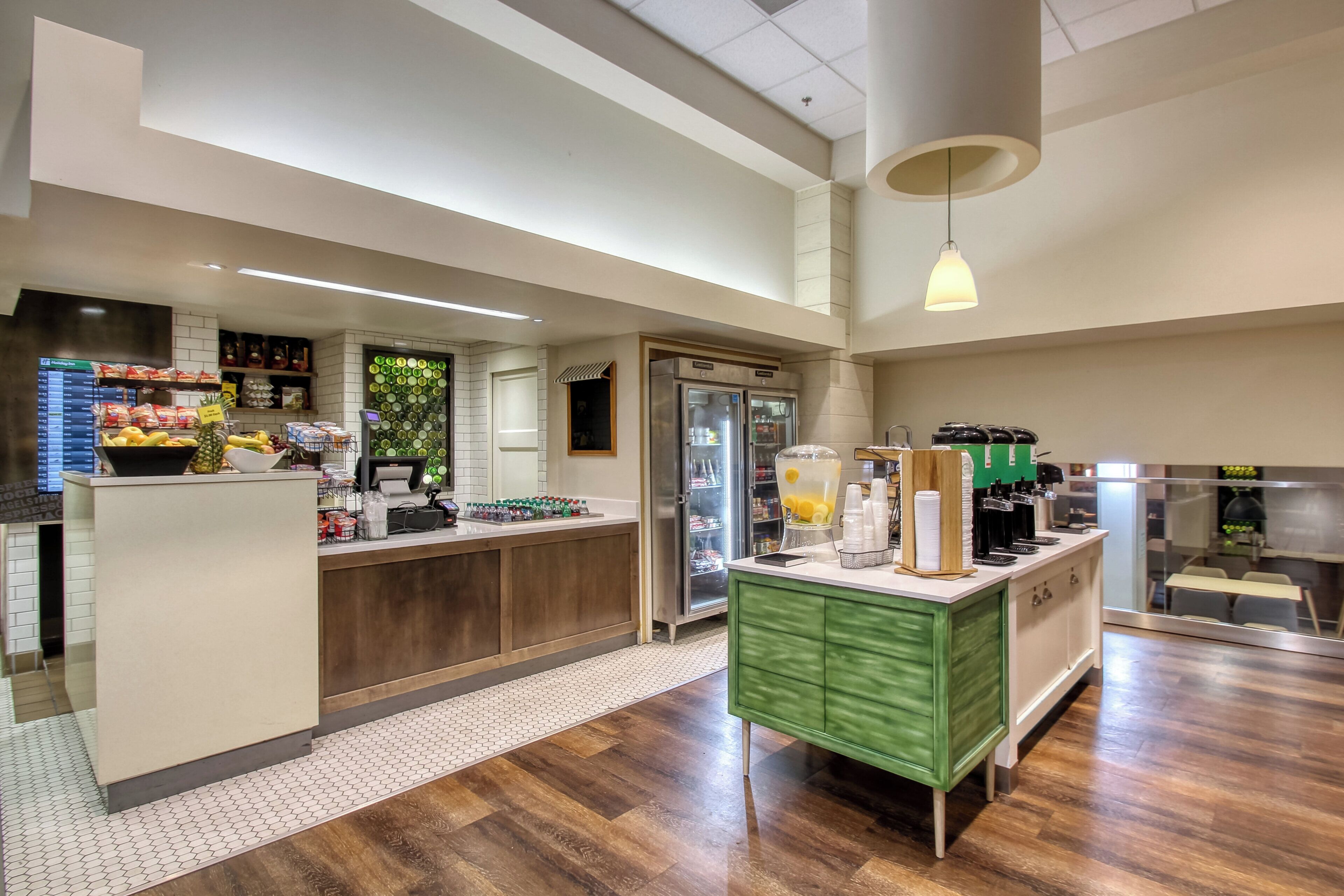 A modern kitchen area with a bar, a refrigerator, and a coffee station.