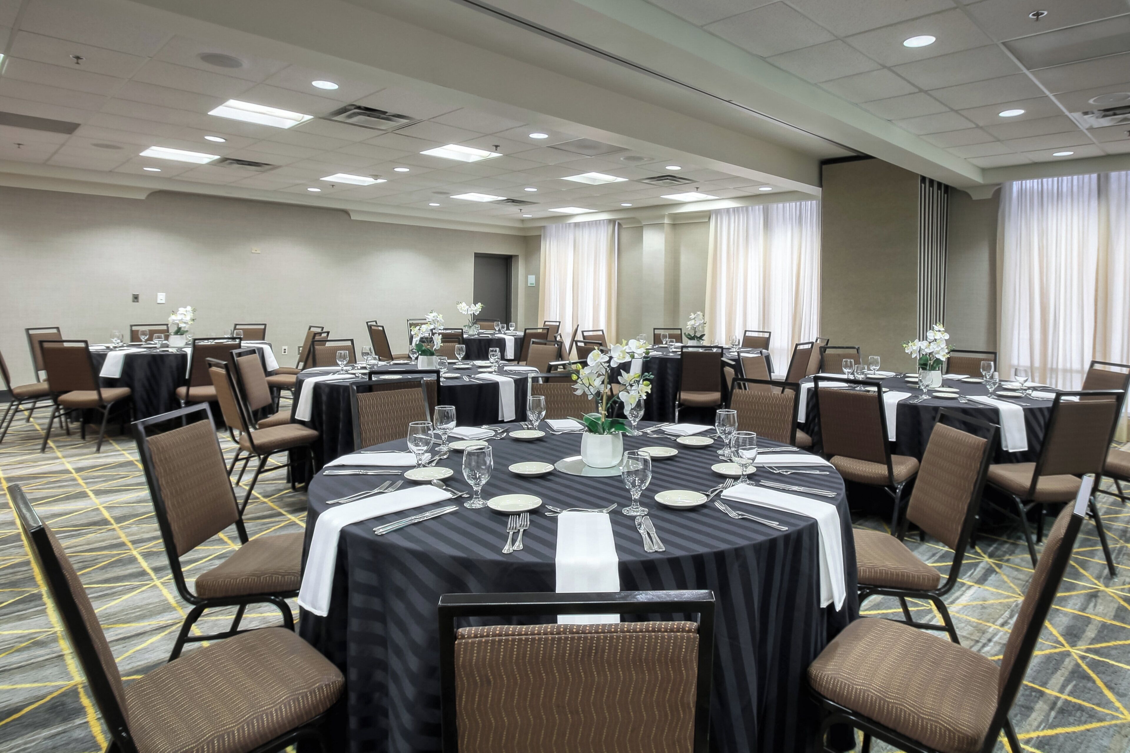 A conference room with round tables, chairs, and a carpeted floor.