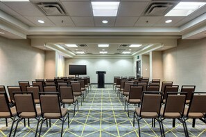 A conference room with rows of chairs, a podium, and a flat-screen TV on the wall. - Holiday Inn Hotel & Suites Atlanta Airport-North by IHG (Atlanta)