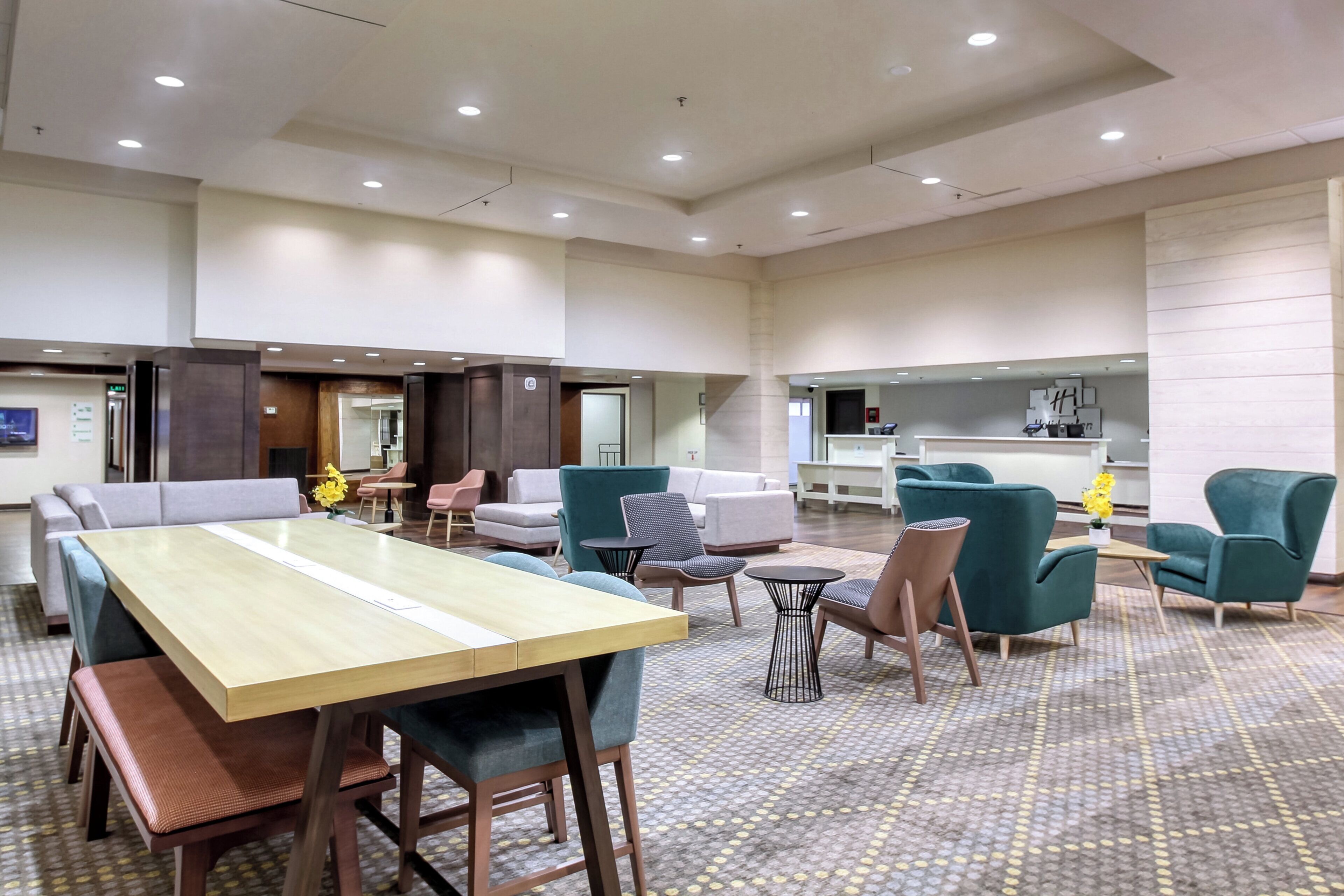 Un hall d’hôtel doté d’une longue table, de plusieurs options d’assises et d’un comptoir d’accueil.
