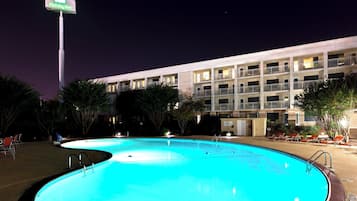 Hotel com piscina, área de estar externa e placa com o nome.