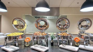 A buffet setup with various food items and serving utensils.
