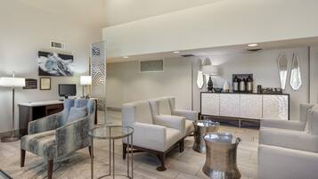 A modern hotel lobby with seating, a reception desk, and a coffee station.