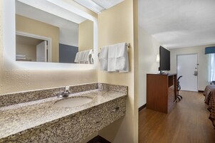 Un baño con lavamanos de granito, un espejo y un perchero para toallas.