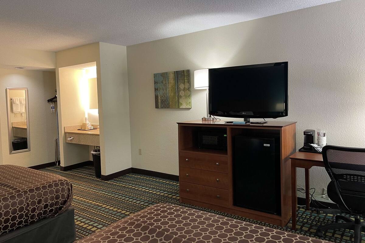 Ein Hotelzimmer mit Bett, Schreibtisch, Computer, Fernseher und Mikrowelle.