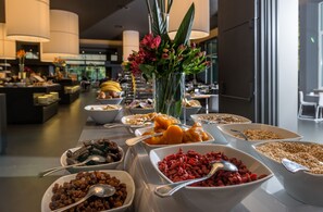 A buffet with various food items and a vase of flowers in the center.