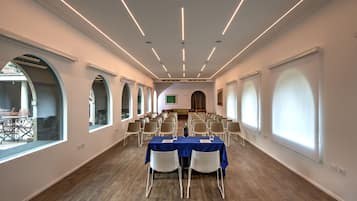 Une salle de conférence avec une longue table, des chaises et un écran de projection à l’avant.