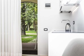 A modern kitchen with a built-in stove, a stainless steel faucet, and a view of a lush garden through an open door.