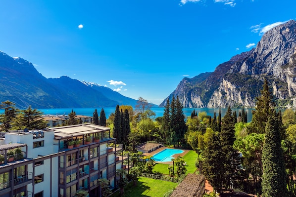 A modern hotel with a pool, surrounded by lush greenery and mountains.