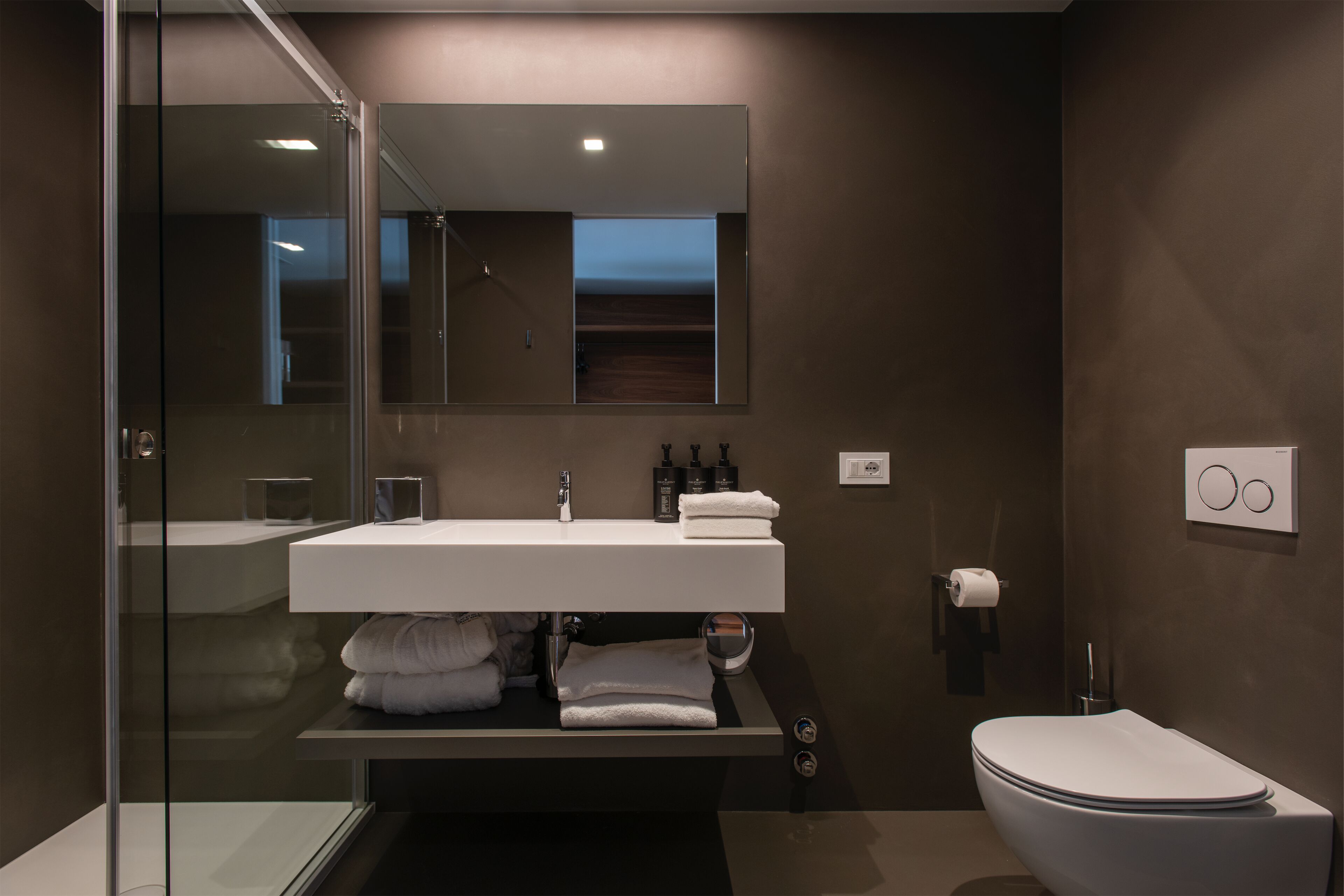 Une salle de bain moderne avec une douche à parois de verre, un lavabo blanc et des toilettes.