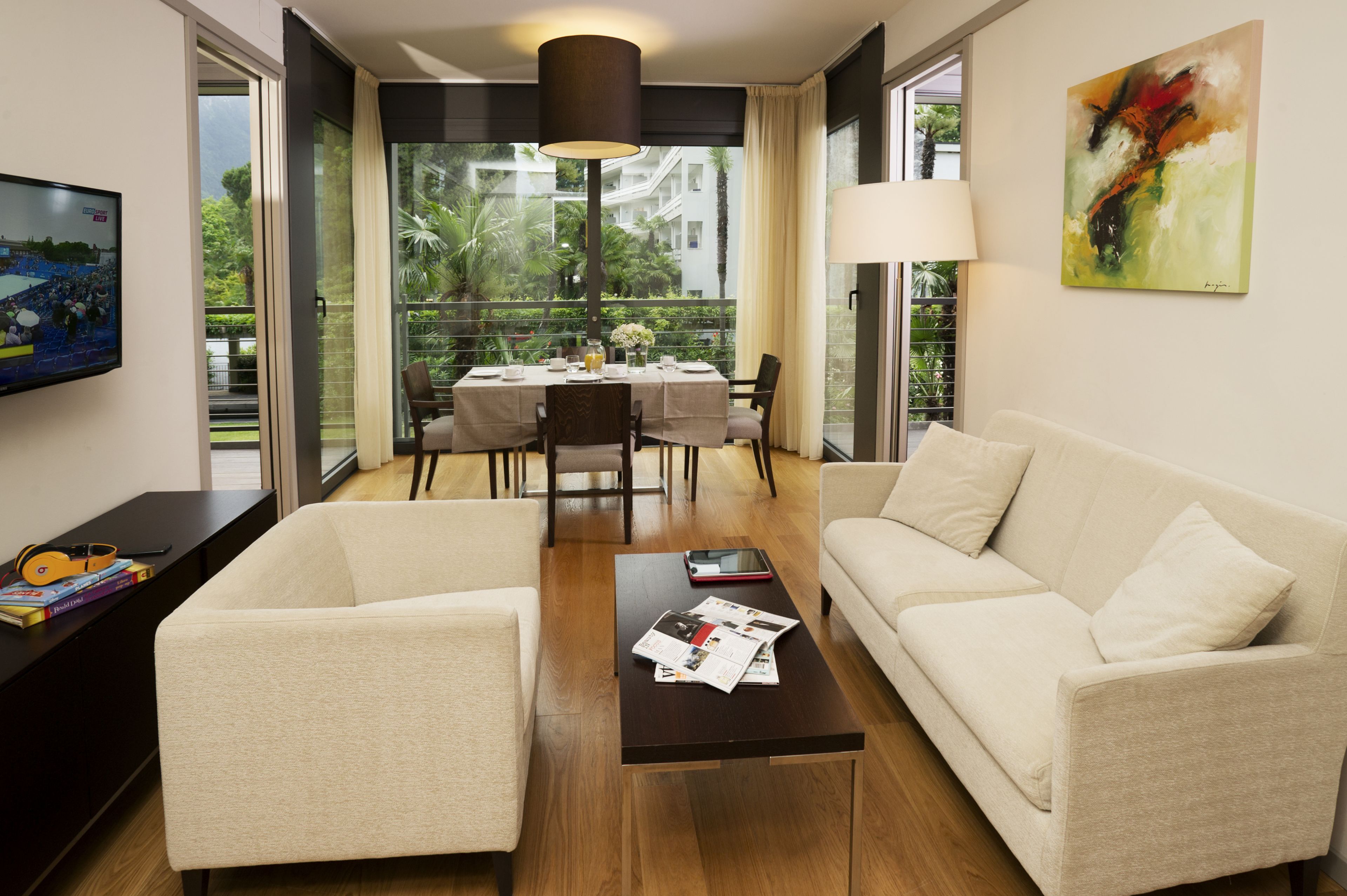 A modern living room with a sofa, armchairs, a coffee table, and a dining area with a table set for four.